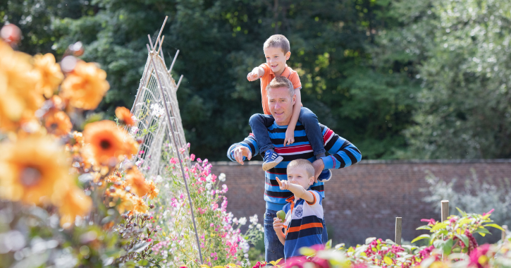 Dad and two children walking through Walled Garden at Auckland Palace Bishop Auckland.